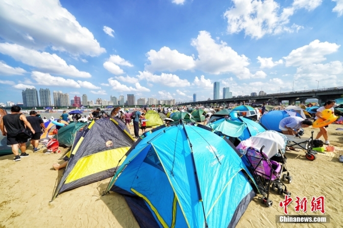 資料圖：哈爾濱市民們在松花江畔的沙灘浴場里扎起帳篷。 <a target='_blank' href='/'>中新社</a>記者 孫漢侖 攝
