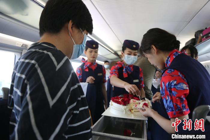 乘務(wù)員與旅客分享生日蛋糕。　周曉陽(yáng) 攝