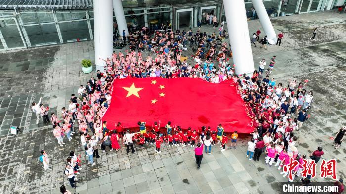 出席快閃音樂(lè)會(huì)人士拉起五星紅旗合影。　主辦方 攝