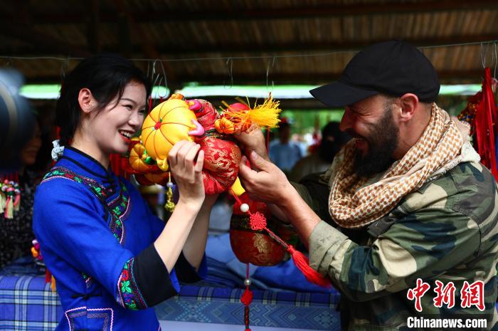 圖為一名來(lái)自德國(guó)的游客與身著民族服裝的壯族姑娘互動(dòng)。　楊必盛 攝