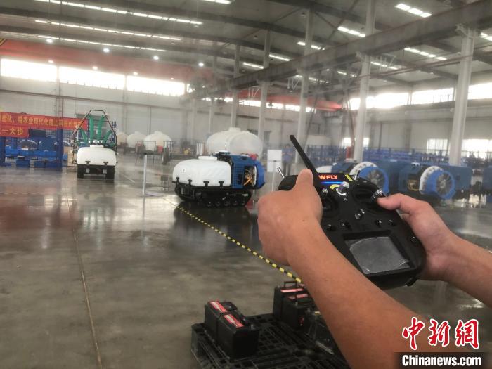 一名工人拿著遙感器，指揮機(jī)器人進(jìn)行“農(nóng)藥”噴灑作業(yè)。　劉林 攝