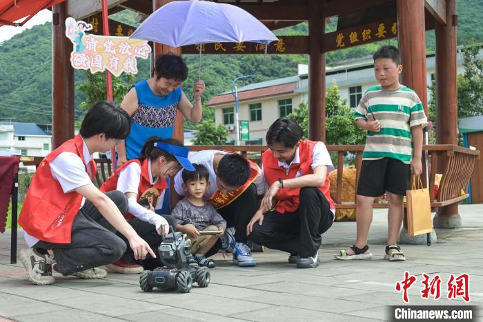 圖為學(xué)子們指導(dǎo)小朋友使用機(jī)器人?！￡愐圾Q 攝