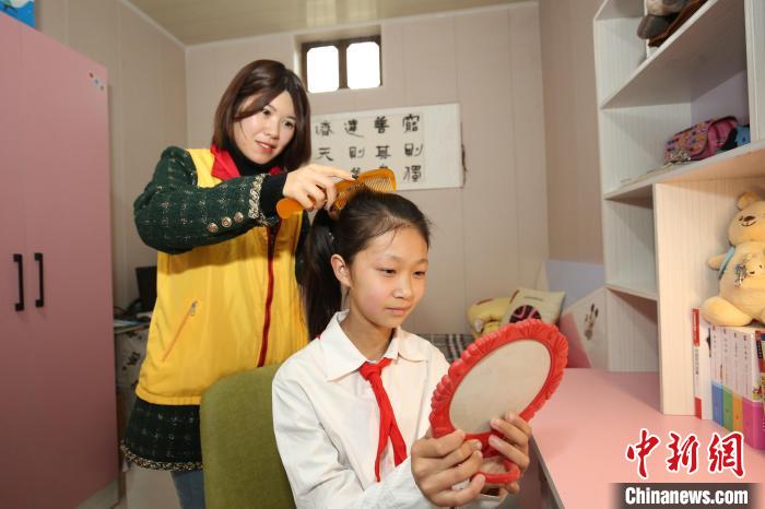 鄒城市“希望小屋”愛心媽媽志愿服務(wù)隊志愿者為兒童扎辮子。　王雪莉 攝