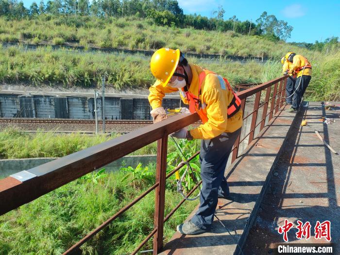 圖為高溫下南寧工務(wù)段橋梁工全副武裝對(duì)鐵路橋梁人行道欄桿打磨除銹?！●T博 攝
