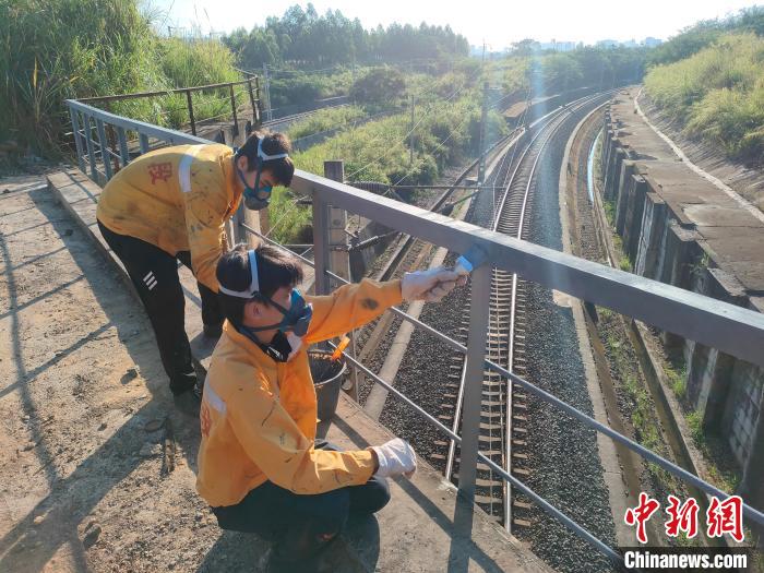 圖為高溫下南寧工務(wù)段橋梁工全副武裝對(duì)鐵路橋梁人行道欄桿打磨除銹?！●T博 攝