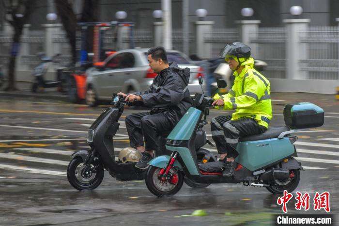 圖為海口市民冒雨出行。　駱云飛 攝