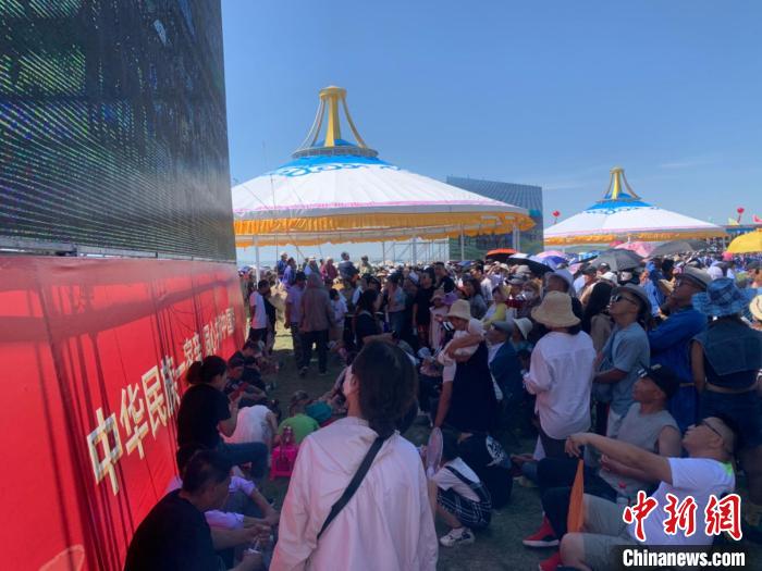 圖為沒有擠進(jìn)座位席的人們，在會場一側(cè)的大屏幕下觀看演出?！W藍(lán) 攝