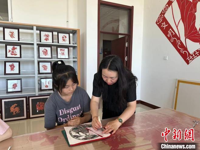 圖為胡穎指導(dǎo)學(xué)員學(xué)習(xí)剪紙藝術(shù)?！罹靶?攝