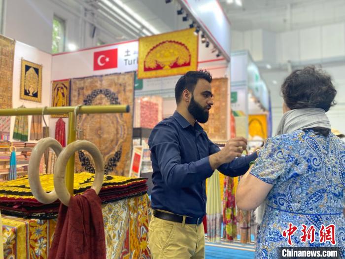 土耳其國(guó)家館工作人員向游客展示當(dāng)?shù)匚膭?chuàng)產(chǎn)品。中新社記者張瑋攝