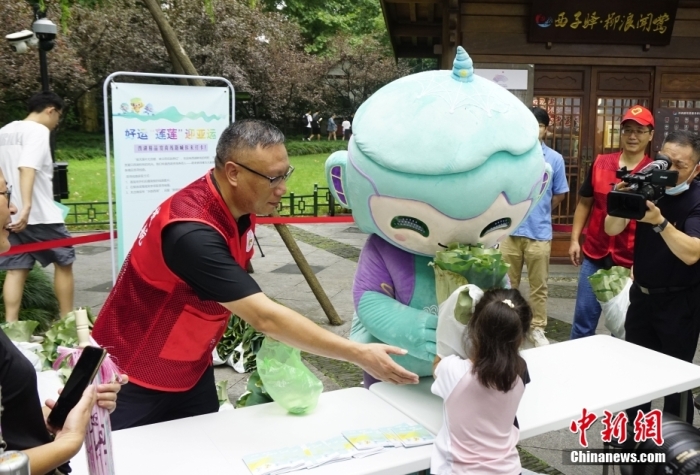 杭州亞運會吉祥物“琮琮”“宸宸”“蓮蓮”在浙江杭州西湖畔參加蓮蓬荷葉義賣活動，圖為亞運會吉祥物“蓮蓮”將分包好的蓮蓬、荷葉交給顧客。<a target='_blank' href='/'>中新社</a>發(fā) 王瓊苓 攝