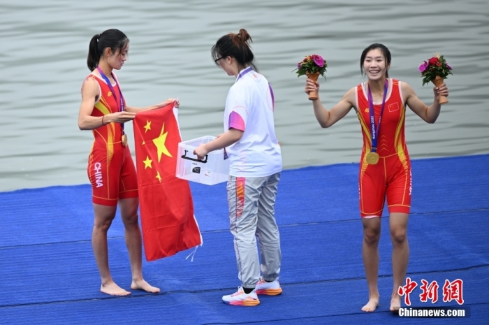 9月24日，杭州第19屆亞運會賽艇女子輕量級雙人雙槳決賽在浙江杭州舉行，中國組合鄒佳琪、邱秀萍以7分06秒78的成績奪冠。這是本屆亞運會的首枚金牌。圖為邱秀萍(左)在頒獎儀式后整理國旗。<a target='_blank' href='/'>中新社</a>記者 王剛 攝