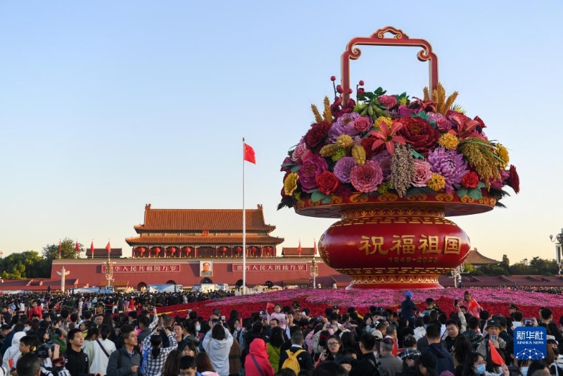 10月1日，在觀看升旗儀式后，人們?cè)诒本┨彀查T廣場(chǎng)參觀。（圖源：新華社）