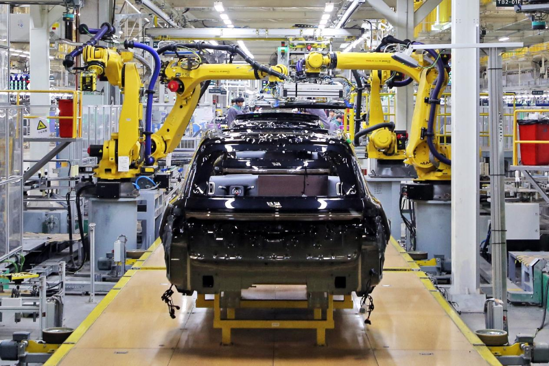 2023年12月10日，江蘇常州一汽車基地的生產(chǎn)車間，機(jī)器臂在組裝新能源汽車。