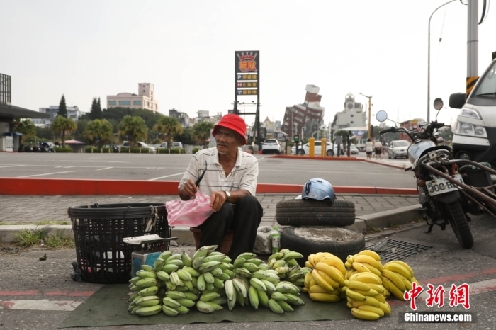資料圖：臺灣花蓮市區(qū)博愛路早市，商販在街頭擺攤售賣水果，不遠處是因震傾斜嚴重的天王星大樓。 中新社記者 楊程晨 攝.jpg