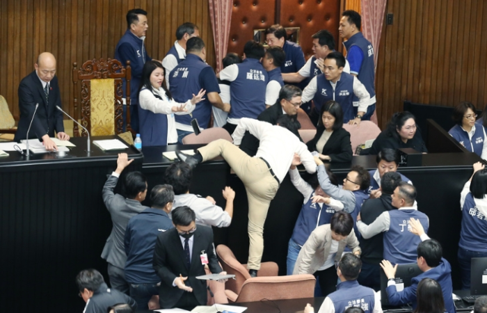 民進黨立委郭國文（中背影者）卻翻上桌，遭國民黨立委攔阻