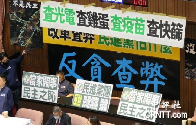 “立院”議場(chǎng)內(nèi)貼滿藍(lán)綠白的布條海報(bào)，上面寫著“查光電、查疫苗、查快篩”等字