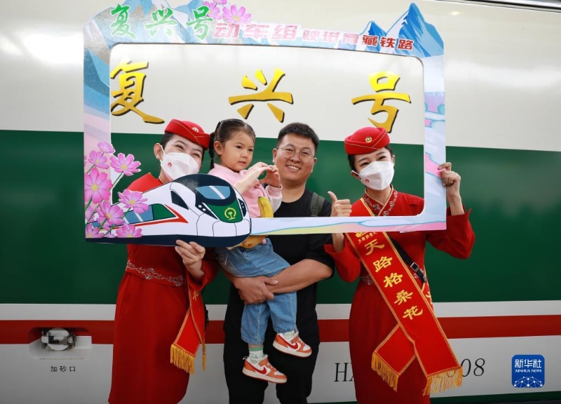 2023年7月1日，乘客與乘務(wù)人員在西寧至格爾木動(dòng)車組首發(fā)列車前合影留念。（圖源：新華社）